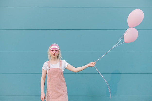 Linda mujer joven en ropa rosa de pie con globos