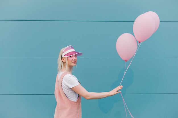 Linda mujer joven en ropa rosa de pie con globos