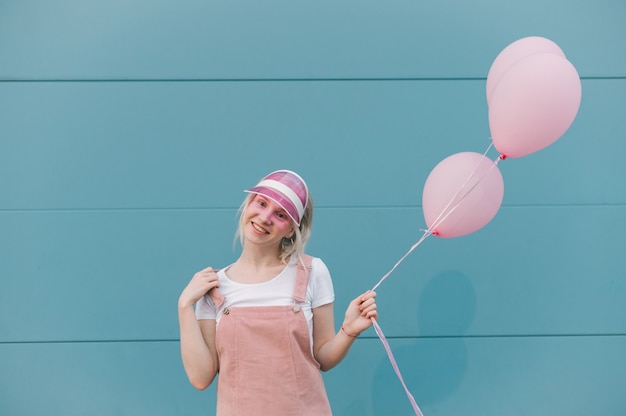 Linda mujer joven en ropa rosa de pie con globos