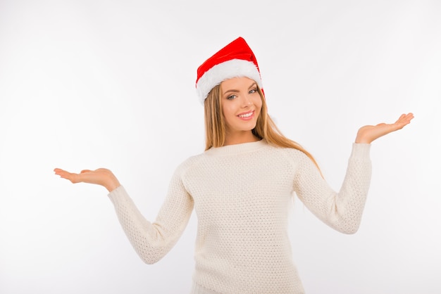 Linda mujer joven con sombrero de santa mostrando algo