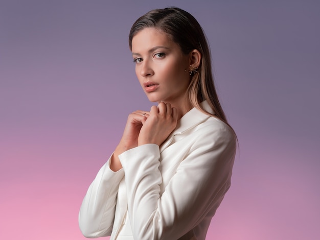 Linda mujer joven con un traje blanco con una chaqueta mirando tristemente a la cámara