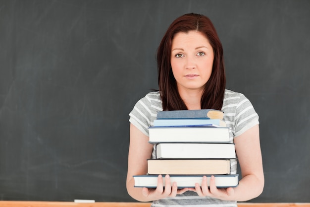 Linda mujer joven trayendo libros pesados