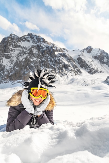 Linda mujer joven vestida con ropa de invierno, gafas de retrato y sombrero divertido de invierno descansando montaña
