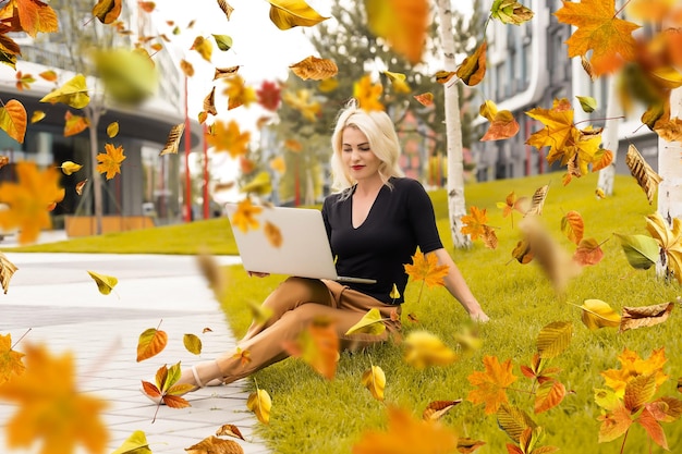 Linda mujer con laptop en el parque de otoño.