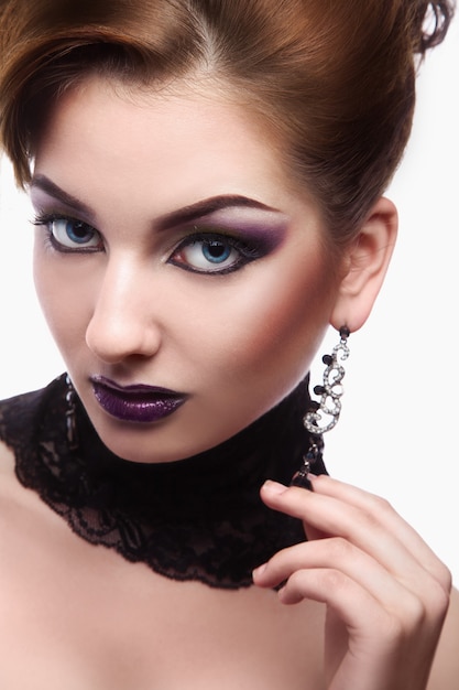 Linda mujer con maquillaje violeta en pared blanca