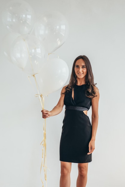 Linda mujer morena de pie sonriendo y jugando con globos