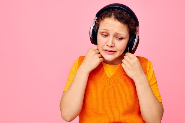 Linda mujer mueca auriculares entretenimiento emociones música rosa fondo inalterado