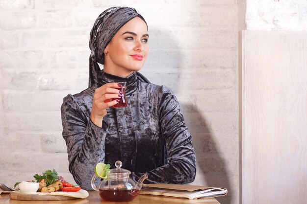 Linda mujer musulmana bebiendo té en un café
