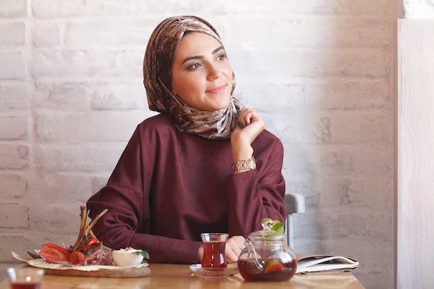 Linda mujer musulmana bebiendo té en café