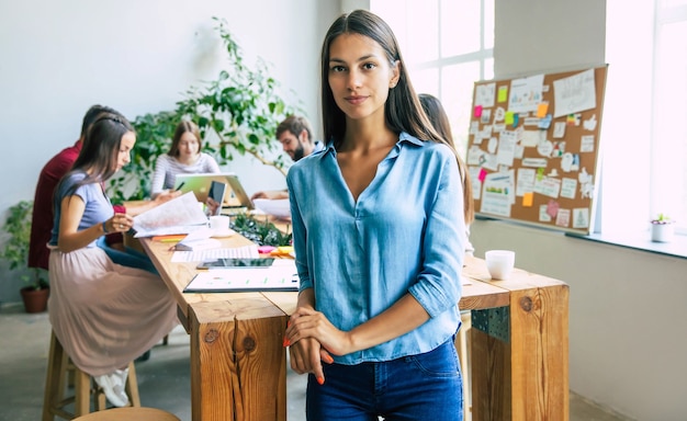 Linda mujer de negocios moderna confiada en ropa casual mira a la cámara y sonriendo. Equipo empresarial moderno de puesta en marcha en la oficina