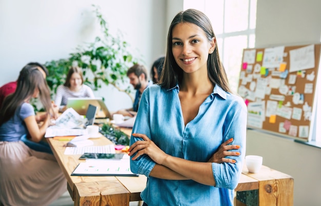 Foto linda mujer de negocios moderna confiada en ropa casual mira a la cámara y sonriendo. equipo empresarial moderno de puesta en marcha en la oficina