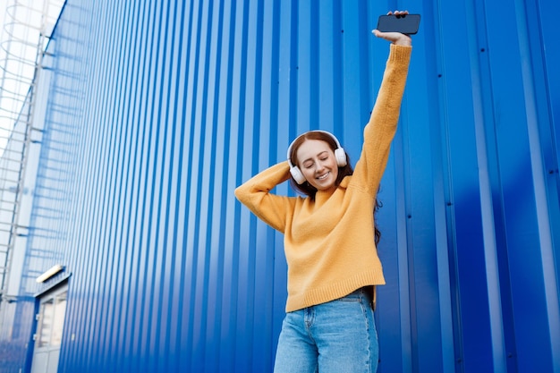 linda mujer pelirroja escucha música en los auriculares