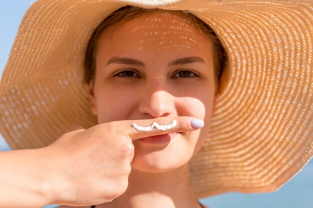 Foto linda mujer está posando con bigote dibujado con crema solar en su dedo debajo de la nariz en el fondo del mar.