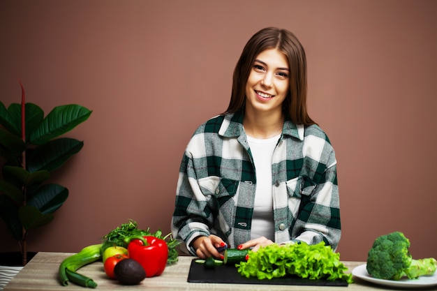 Linda mujer preparando una ensalada de verduras frescas en casa en la cocina