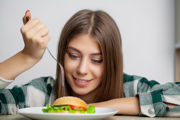 Linda mujer quiere comer hamburguesa dañina