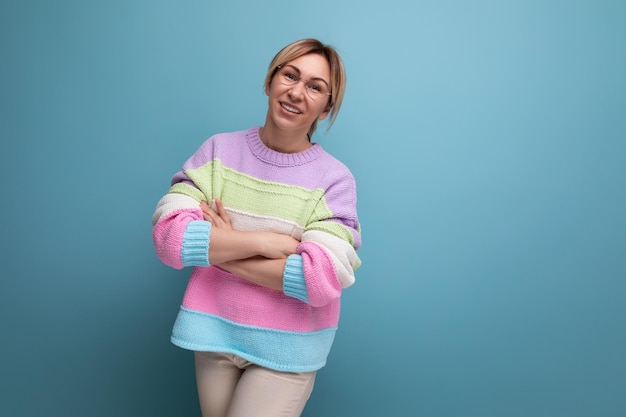 Linda mujer rubia atractiva en un suéter a rayas sonriendo sobre un fondo azul con espacio de copia