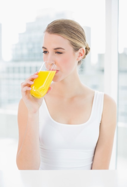 Linda mujer rubia bebiendo jugo de naranja