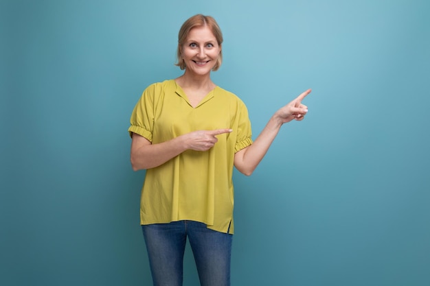 Linda mujer rubia de mediana edad que muestra un espacio vacío con el dedo