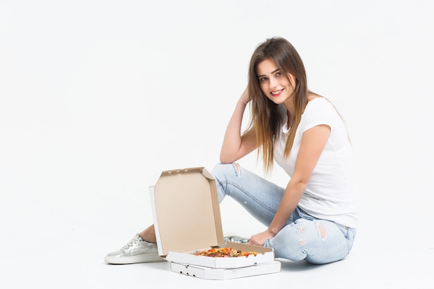 Linda mujer se sienta en el piso con una caja de pizza y toma un pedazo.