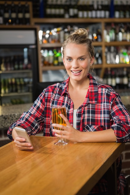 Linda mujer con smartphone y tomando una cerveza