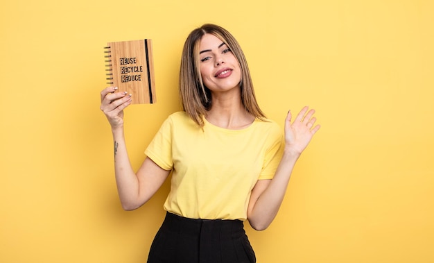 Linda mujer sonriendo alegremente, saludando con la mano, dándote la bienvenida y saludándote. concepto de reciclaje