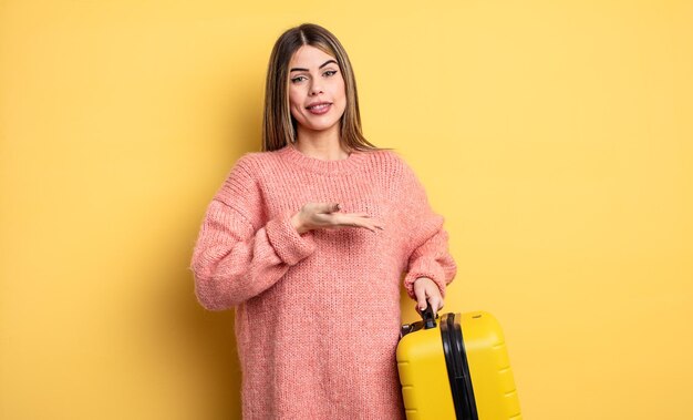 Linda mujer sonriendo alegremente, sintiéndose feliz y mostrando un concepto. concepto de viaje en maleta