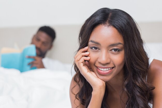 Linda mujer sonriendo a la cámara en la cama