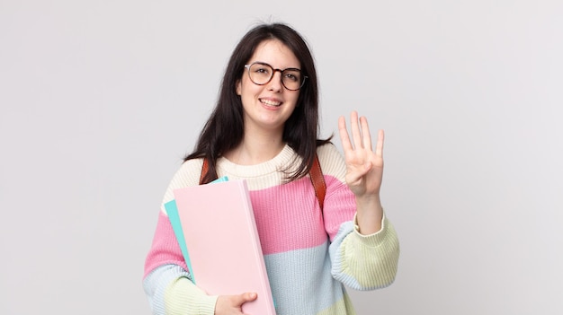 Linda mujer sonriendo y luciendo amigable mostrando el concepto de estudiante universitario número cuatro