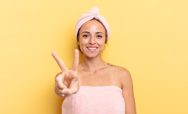 Linda mujer sonriendo y luciendo feliz, gesticulando victoria o paz. concepto de ducha y belleza