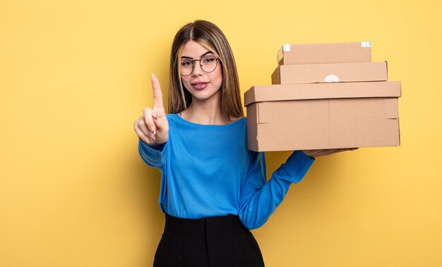 Linda mujer sonriendo con orgullo y confianza haciendo el concepto de cajas de paquetes número uno