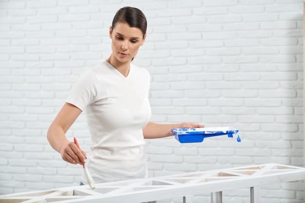 Linda mujer sosteniendo pintura blanca y bastidor de madera de pintura