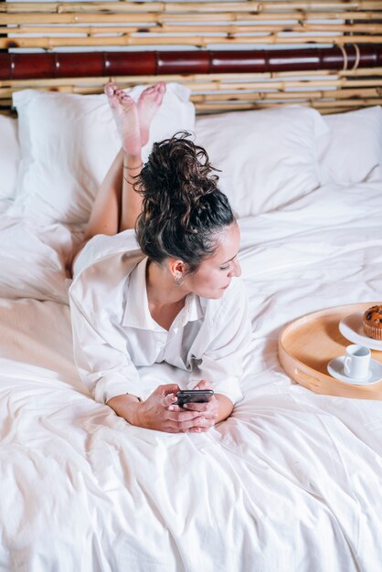 Linda mujer con teléfono en la cama