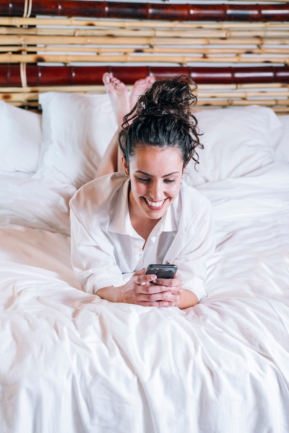 Linda mujer con teléfono en la cama