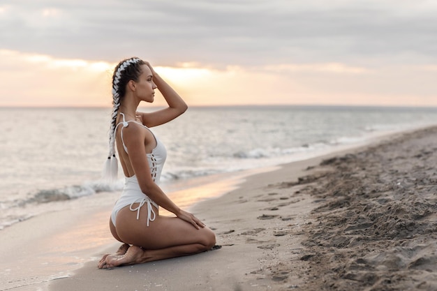 linda mujer en traje de baño en la playa al atardecer
