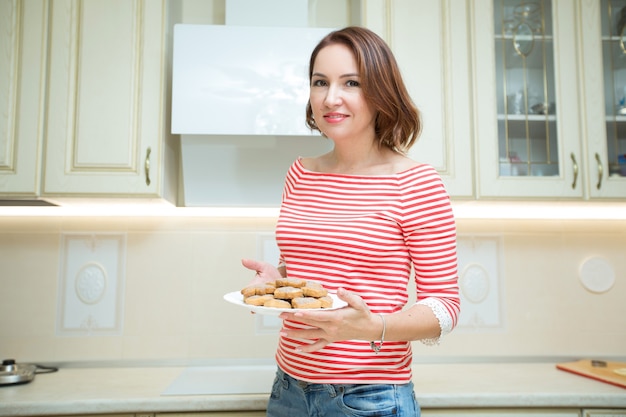 linda mulher adulta com biscoitos nas mãos na cozinha