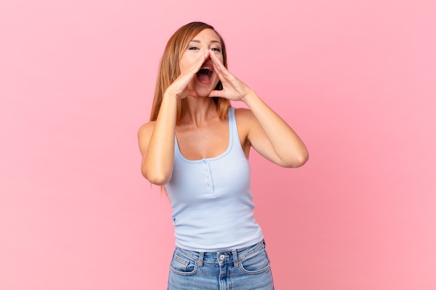 Linda mulher adulta se sentindo feliz, dando um grande grito com as mãos perto da boca