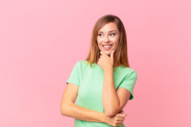 Linda mulher adulta sorrindo com uma expressão feliz e confiante com a mão no queixo