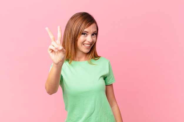 Linda mulher adulta sorrindo e parecendo feliz, gesticulando vitória ou paz