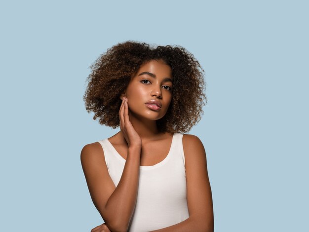 Linda mulher africana camiseta branca retrato corte de cabelo afro tocando seu rosto cor de fundo azul