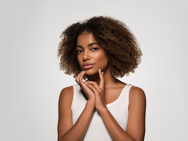 Linda mulher africana camiseta branca retrato corte de cabelo afro tocando seu rosto Cor de fundo cinza