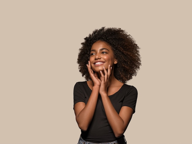 Linda mulher africana camiseta preta retrato corte de cabelo afro tocando seu rosto Cor de fundo marrom