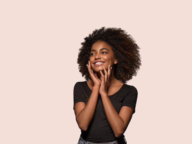 Linda mulher africana camiseta preta retrato corte de cabelo afro tocando seu rosto Cor de fundo rosa