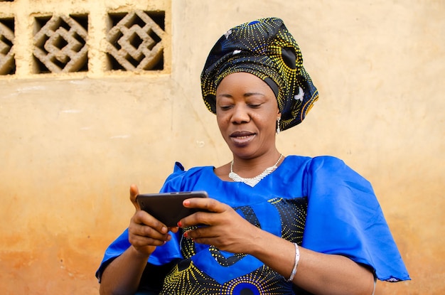 Linda mulher africana sênior olhando no celular em casa