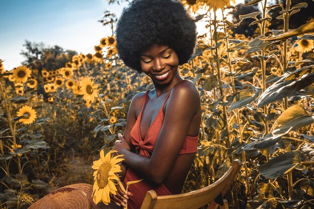 Linda mulher afro-americana com cabelo encaracolado estilo afro em um campo de girassóis.