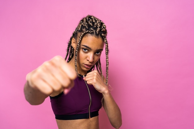 Linda mulher afro-americana com retrato de tranças na parede colorida fazendo exercícios de esporte