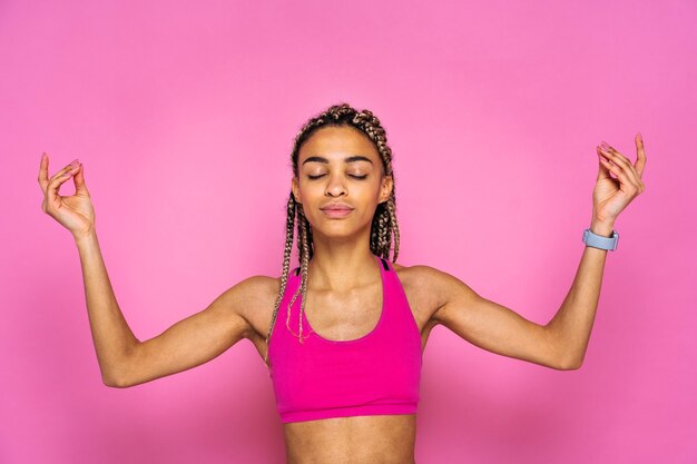 Linda mulher afro-americana com retrato de tranças na parede colorida fazendo exercícios de esporte