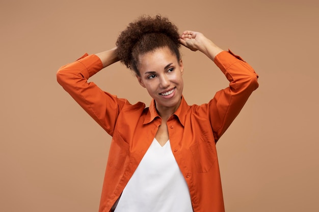 Linda mulher afro-americana em roupas casuais sorrindo olhando de lado fundo bege isolado