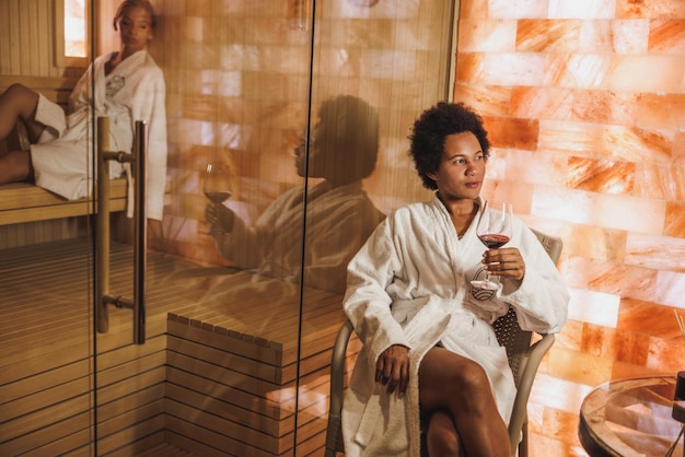 Linda mulher afro-americana madura relaxando em uma caverna de cristal de sal e sauna no centro de spa.