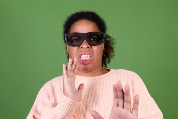 Linda mulher afro-americana na parede verde com óculos de cinema 3d assistindo filme emoção de nojo