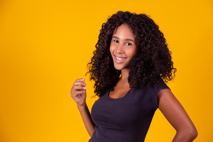 Foto linda mulher afro-americana olhando para a câmera retrato de uma jovem alegre com penteado afro menina de beleza com cabelo encaracolado